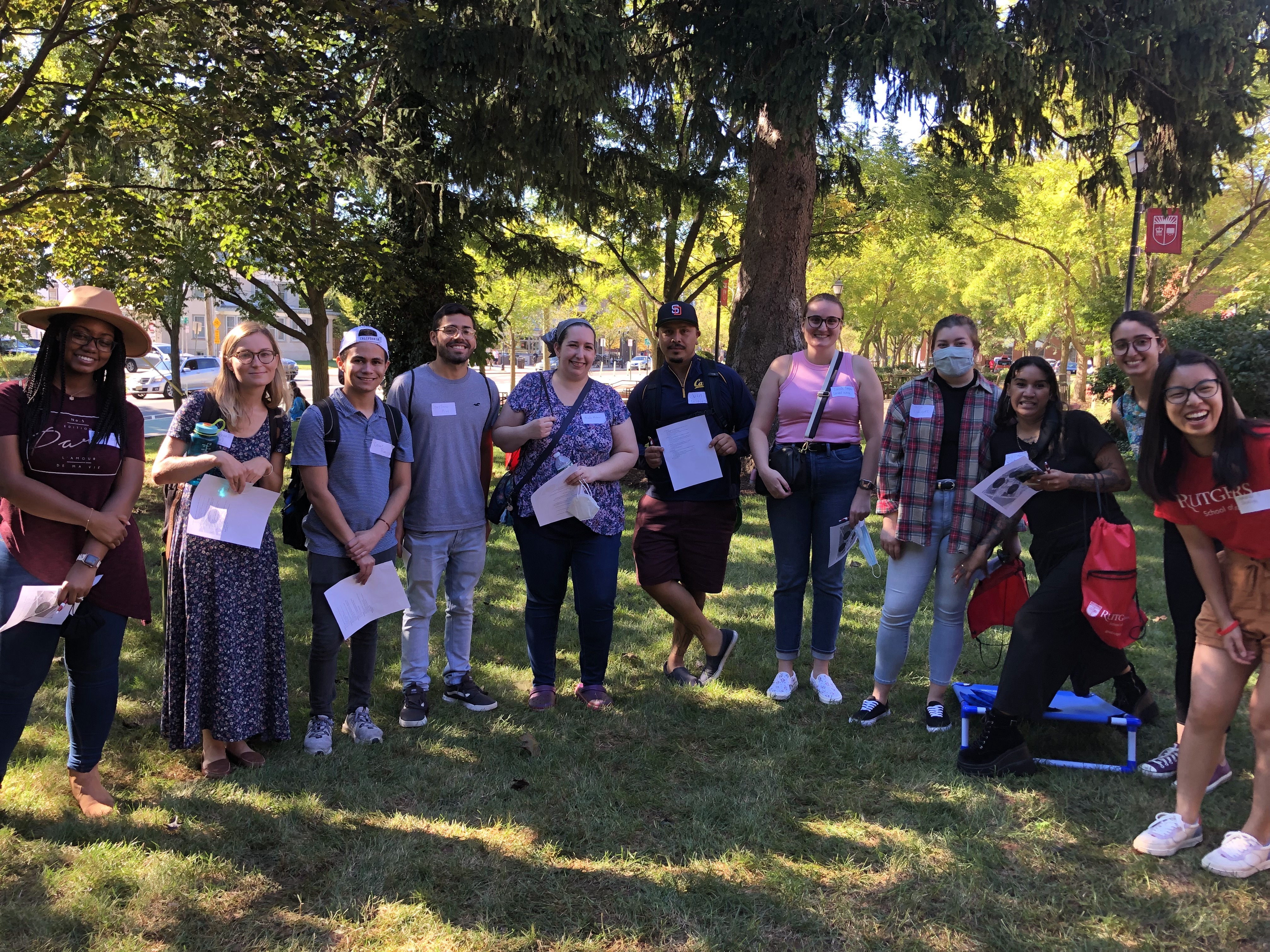 Students standing on a lawn in a row, smiling.