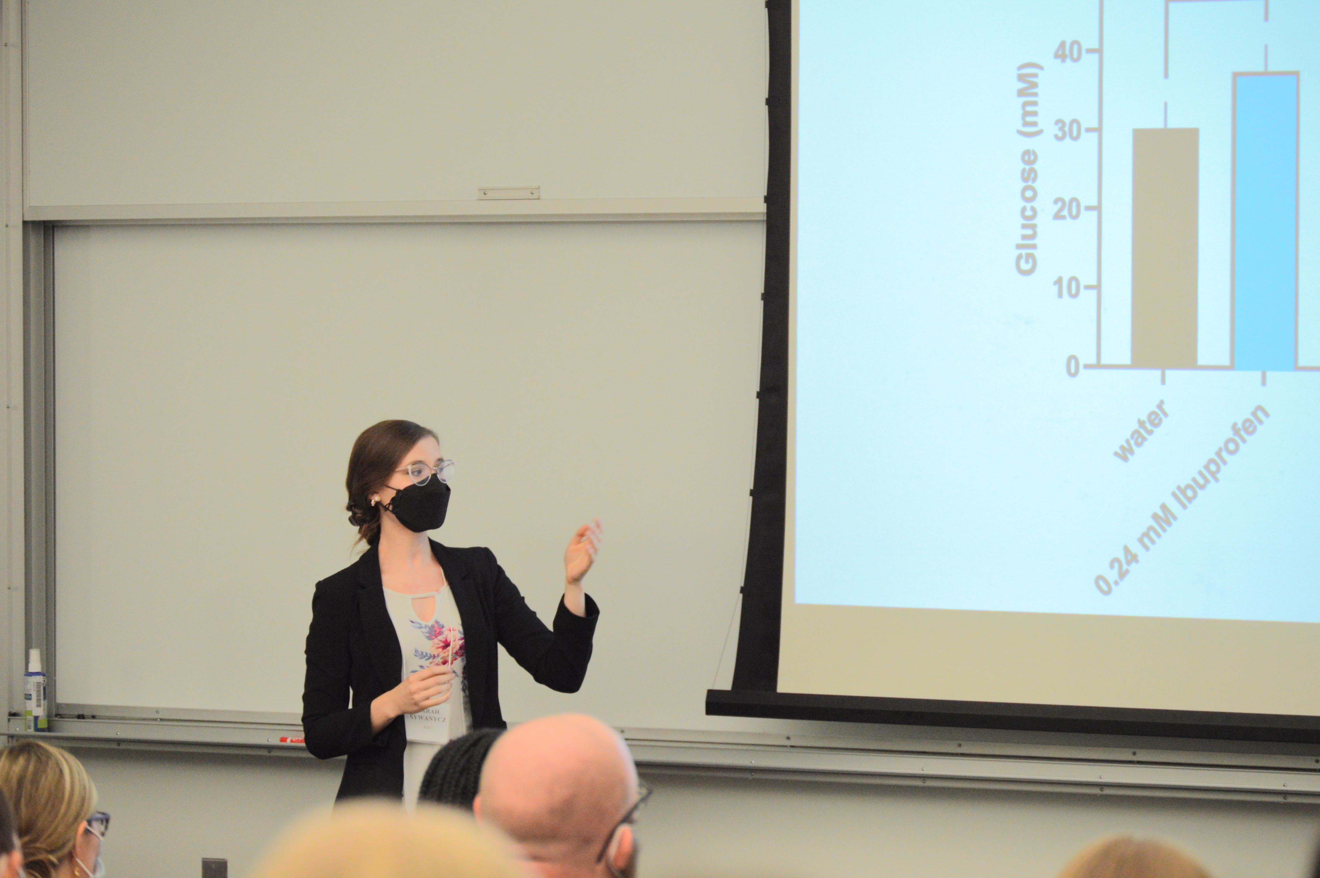 Woman standing in front of powerpoint presentation at the front of a classroom.